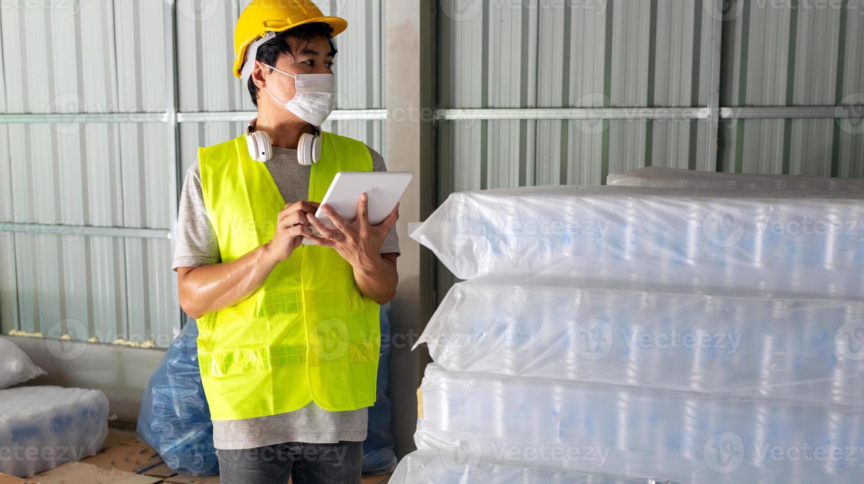 Aziatisch Mens arbeider controle de voorraad van plastic flessen in de magazijn en vergelijken de balanceren aantal in de systeem na levering Verzending. gebruik makend van een tablet naar bijwerken online voorraad foto