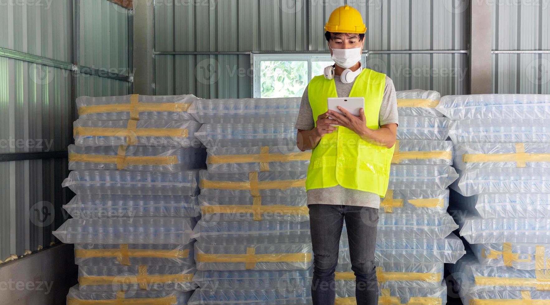 Aziatisch Mens arbeider controle de voorraad van plastic flessen in de magazijn en vergelijken de balanceren aantal in de systeem na levering Verzending. gebruik makend van een tablet naar bijwerken online voorraad foto