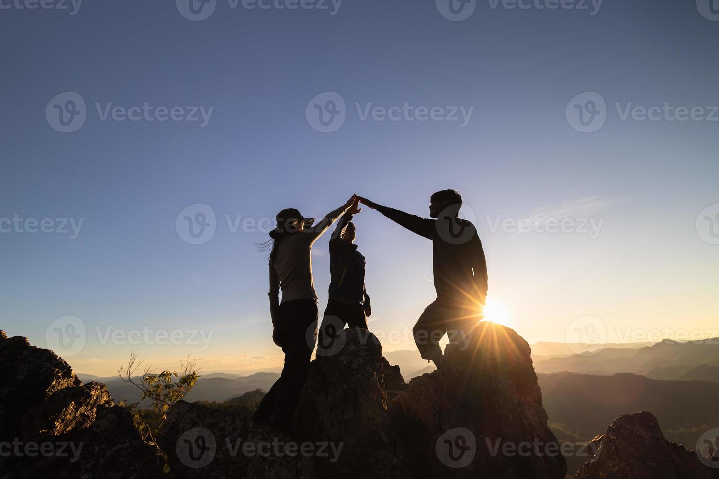 silhouet van samenspel van drie wandelaar helpen elk andere Aan top van berg beklimming team. samenspel vriendschap wandelen helpen elk andere vertrouwen bijstand silhouet in bergen, zonsopkomst. foto