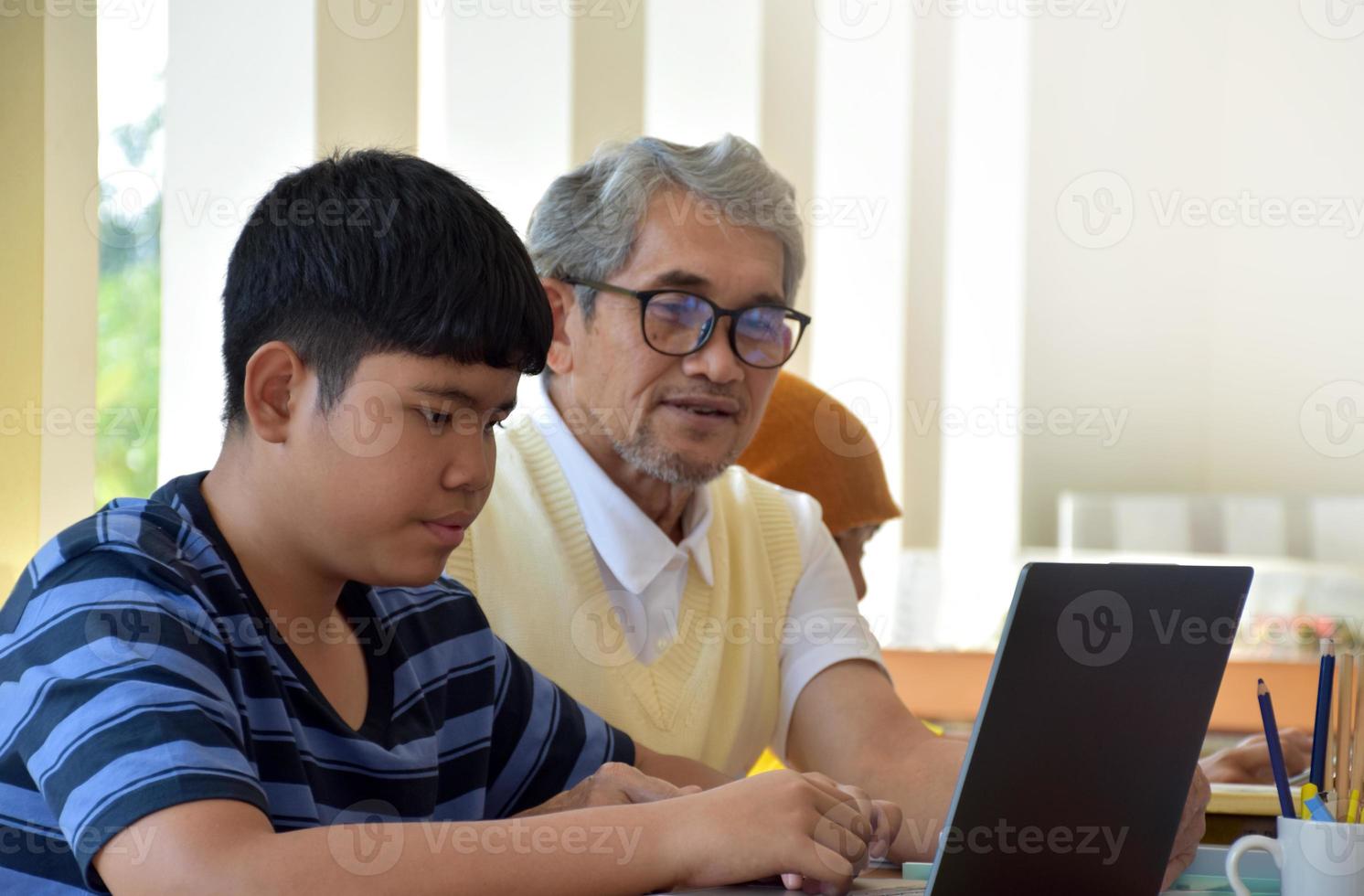 Aziatisch bejaarde leraar en jong tieners omgeving binnen de kamer naar raadplegen en naar Doen de school- project werk, bejaarde leraar helpt kinderen naar opnieuw bevallen problemen en adviezen hen naar krijgen een mooi zo cijfer. foto