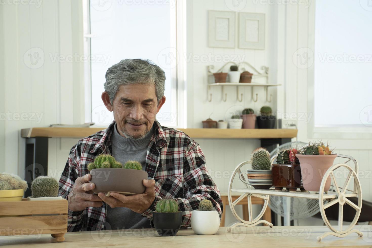 portret ouderen senior Aziatisch Mens zit in de buurt glas venster in de ochtend- naar werk van huis en controle zijn bedrijf Aan zijn laptop Aan tafel ernstig, zacht en selectief focus. foto