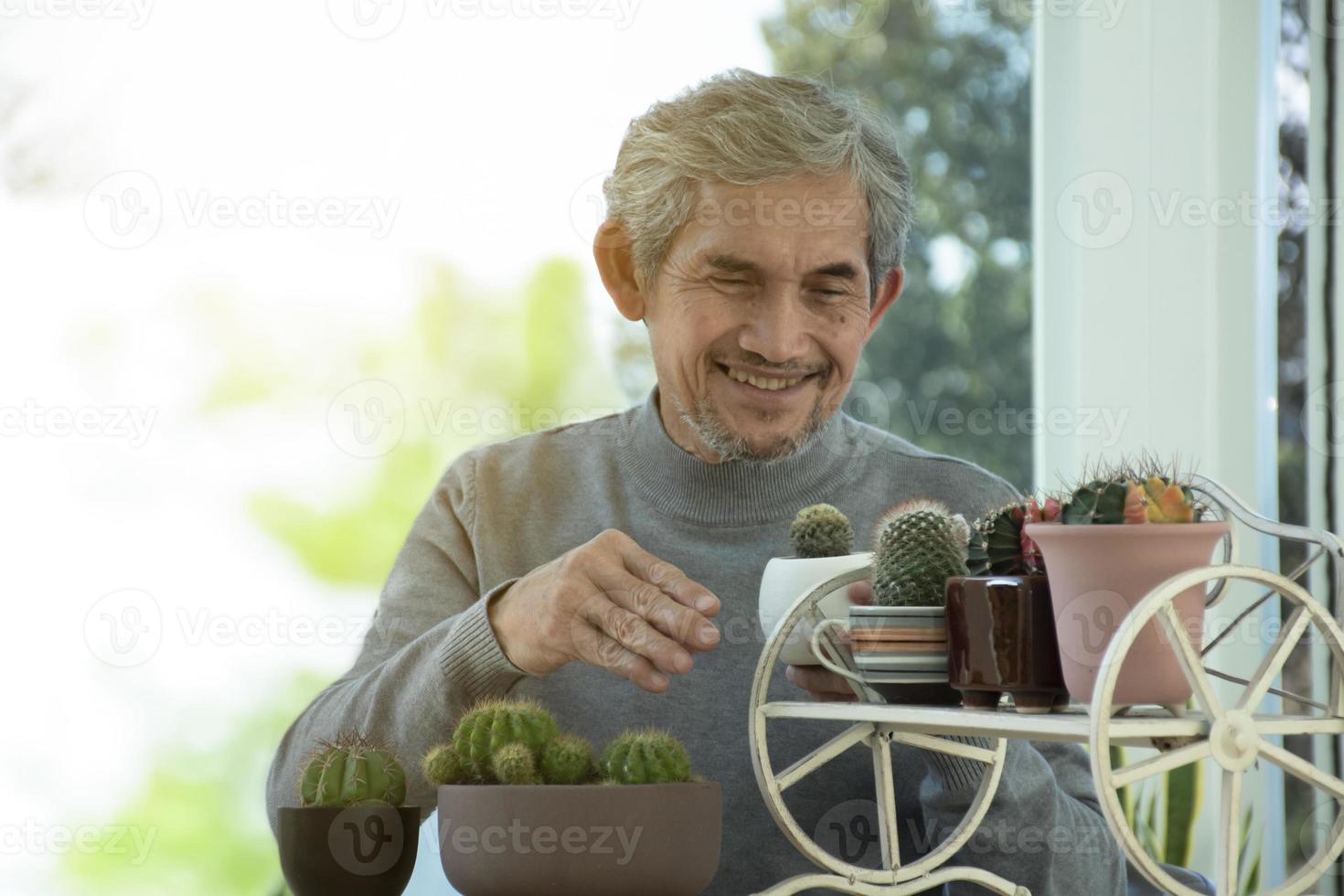 portret ouderen senior Aziatisch Mens zit in de buurt glas venster in de ochtend- naar werk van huis en controle zijn bedrijf Aan zijn laptop Aan tafel ernstig, zacht en selectief focus. foto