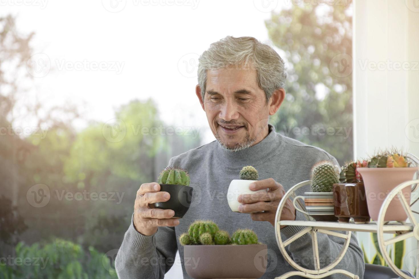 portret ouderen senior Aziatisch Mens zit in de buurt glas venster in de ochtend- naar werk van huis en controle zijn bedrijf Aan zijn laptop Aan tafel ernstig, zacht en selectief focus. foto