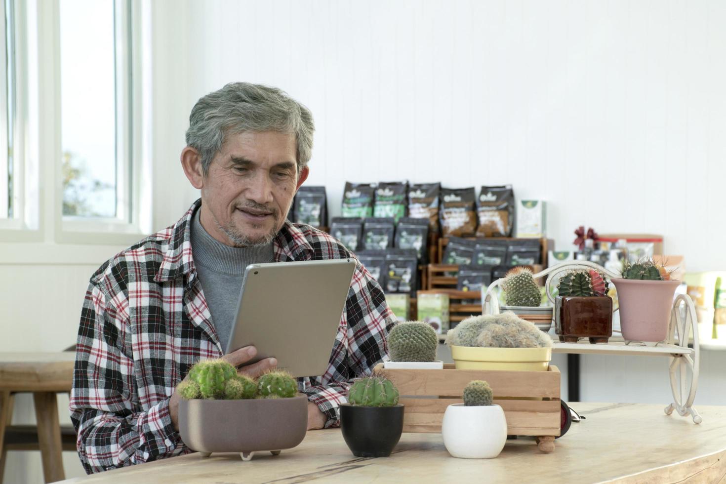 portret ouderen senior Aziatisch Mens zit in de buurt glas venster in de ochtend- naar werk van huis en controle zijn bedrijf Aan zijn laptop Aan tafel ernstig, zacht en selectief focus. foto