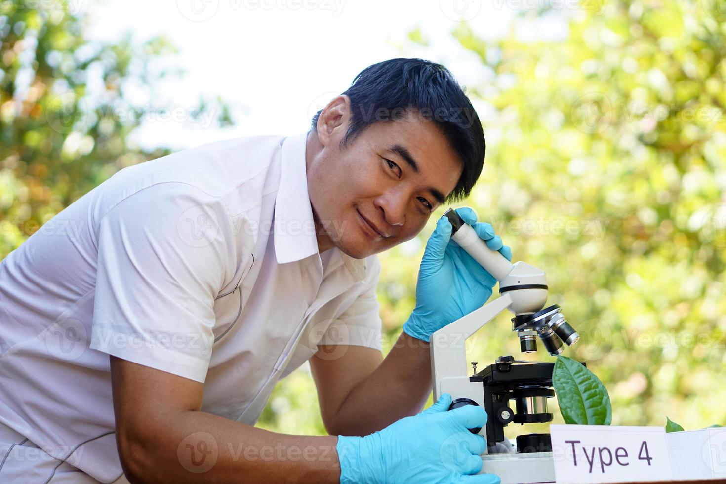 portret van knap Aziatisch Mens wetenschap leraar Doen experiment buitenshuis, draagt blauw handschoenen, gebruik microscoop. concept, wetenschap onderwerp, project werk. experiment, onderwijs. buitenshuis klas. foto