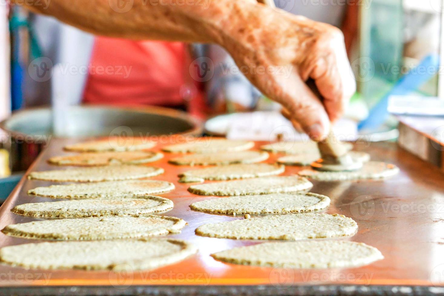 oud man's hand- is maken snoepgoed Thais krokant pannenkoek voor klanten. in afbeelding hij zetten gouden draden toetje Aan top van zoet room en deeg bladen. foto