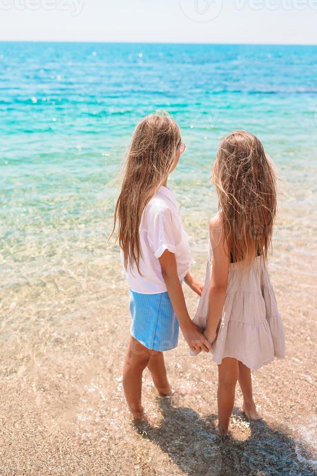 gelukkig kinderen spatten in de golven gedurende zomer vakantie Aan tropisch strand. meisjes Speel Bij de zee. foto