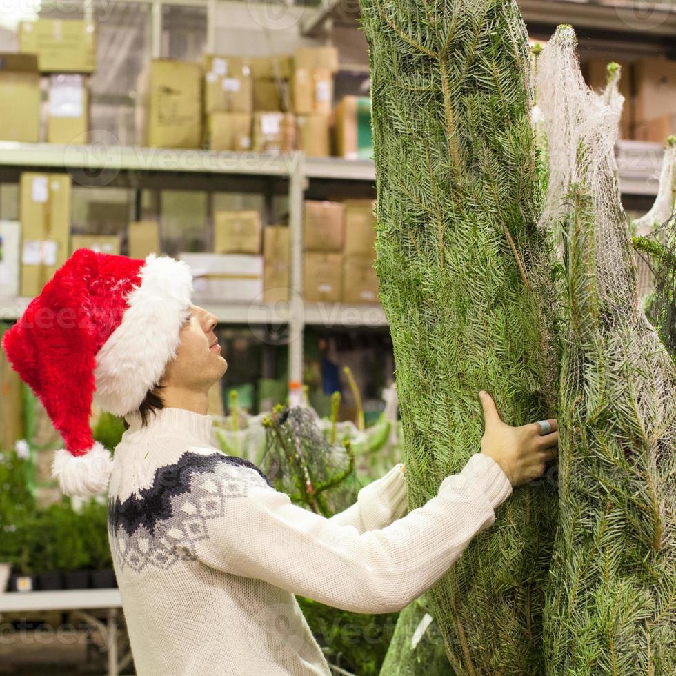 jong vader in de kerstman hoed buying Kerstmis boom foto