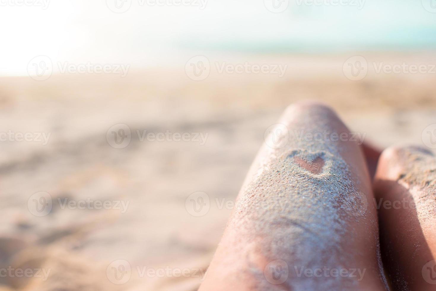 vrouw voeten met hart tekening door zand foto