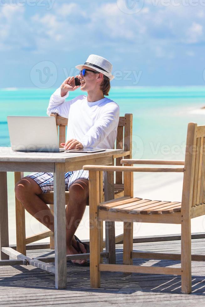 jong bedrijf Mens roeping door cel telefoon Aan wit strand foto