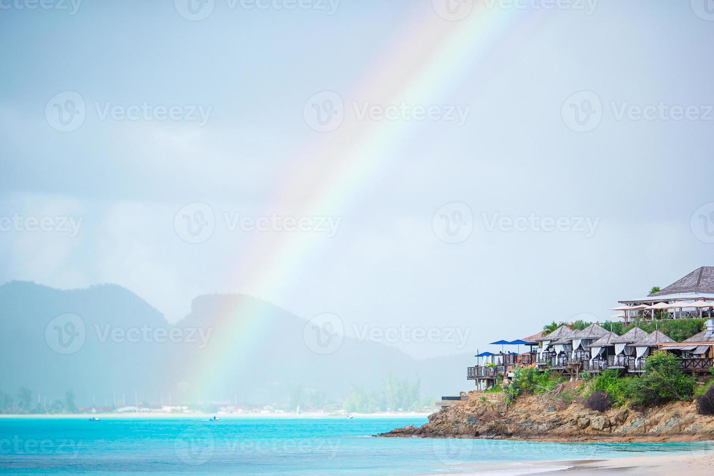 tropisch strand met turkoois water in de oceaan, wit zand en kleurrijk regenboog foto