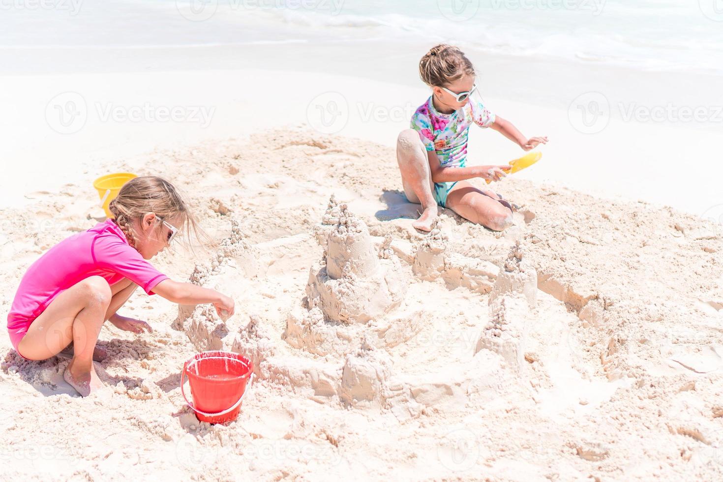 twee weinig gelukkig meisjes hebben een veel van pret Bij tropisch strand spelen samen foto