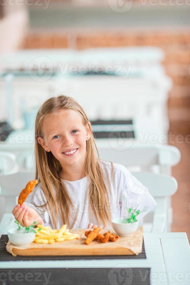 schattig klein meisje aan het eten op het terras foto