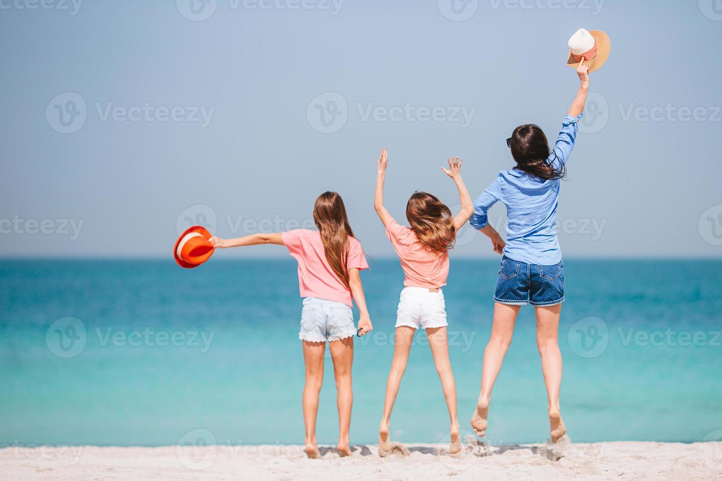 schattige kleine meisjes en jonge moeder op tropisch wit strand foto