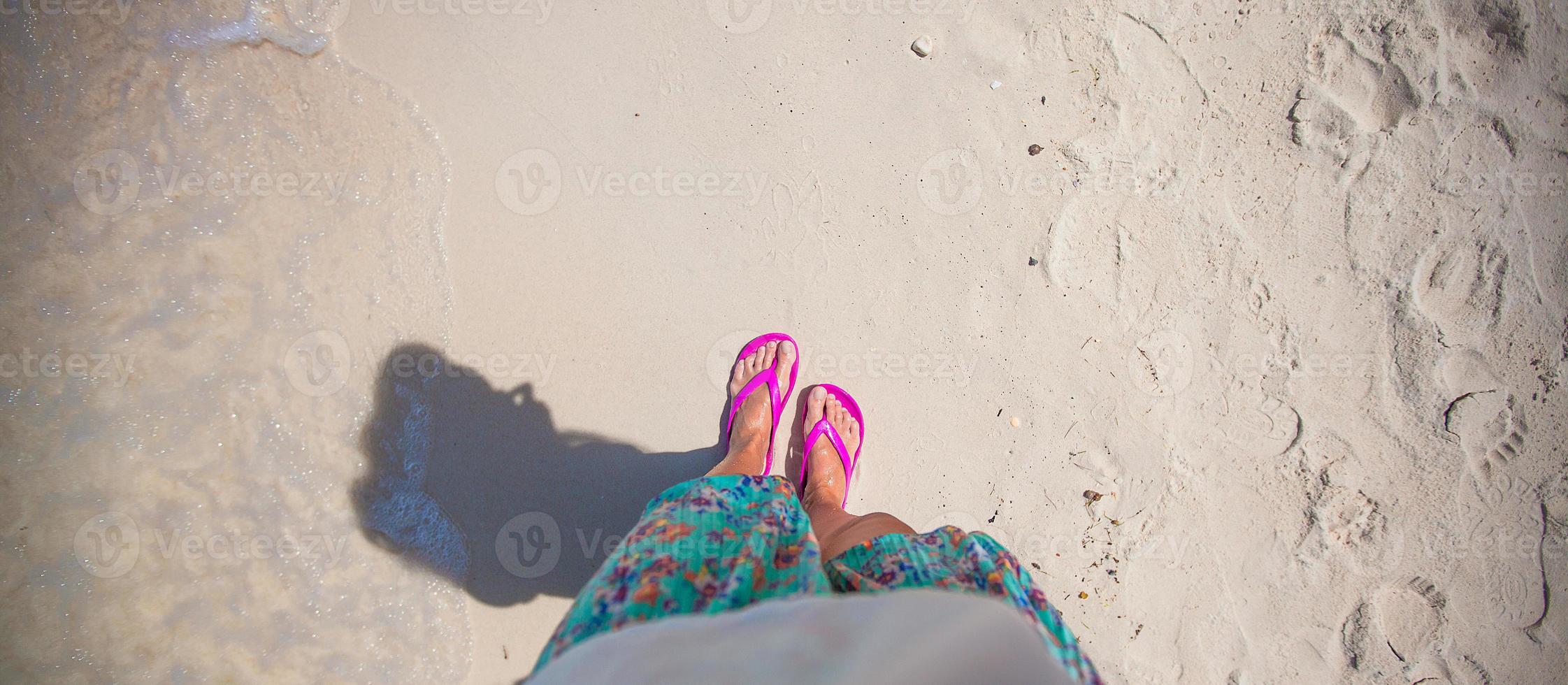 detailopname van een vrouw voet in de schalie Aan zand strand foto