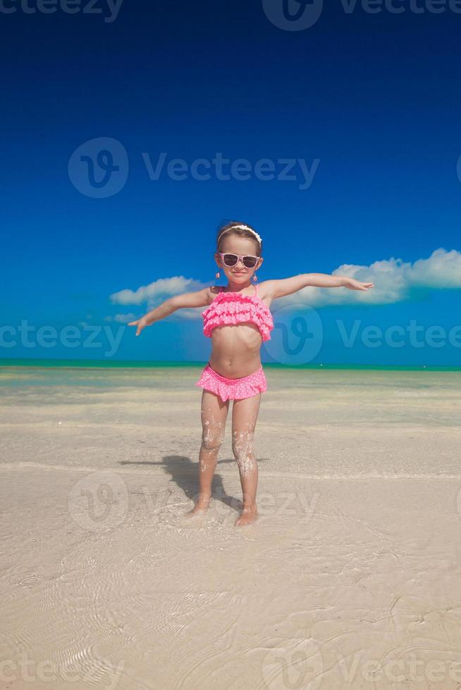 weinig meisje verspreiding haar armen staand Bij de wit strand foto