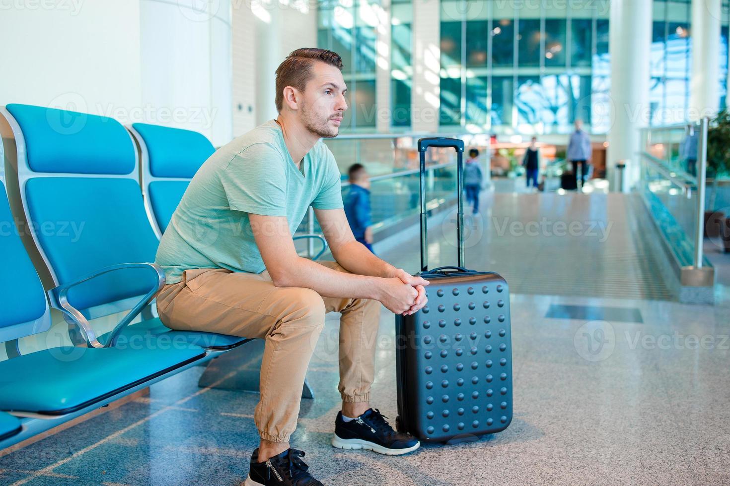 jong Mens in een luchthaven lounge aan het wachten voor vlucht vliegtuigen. foto