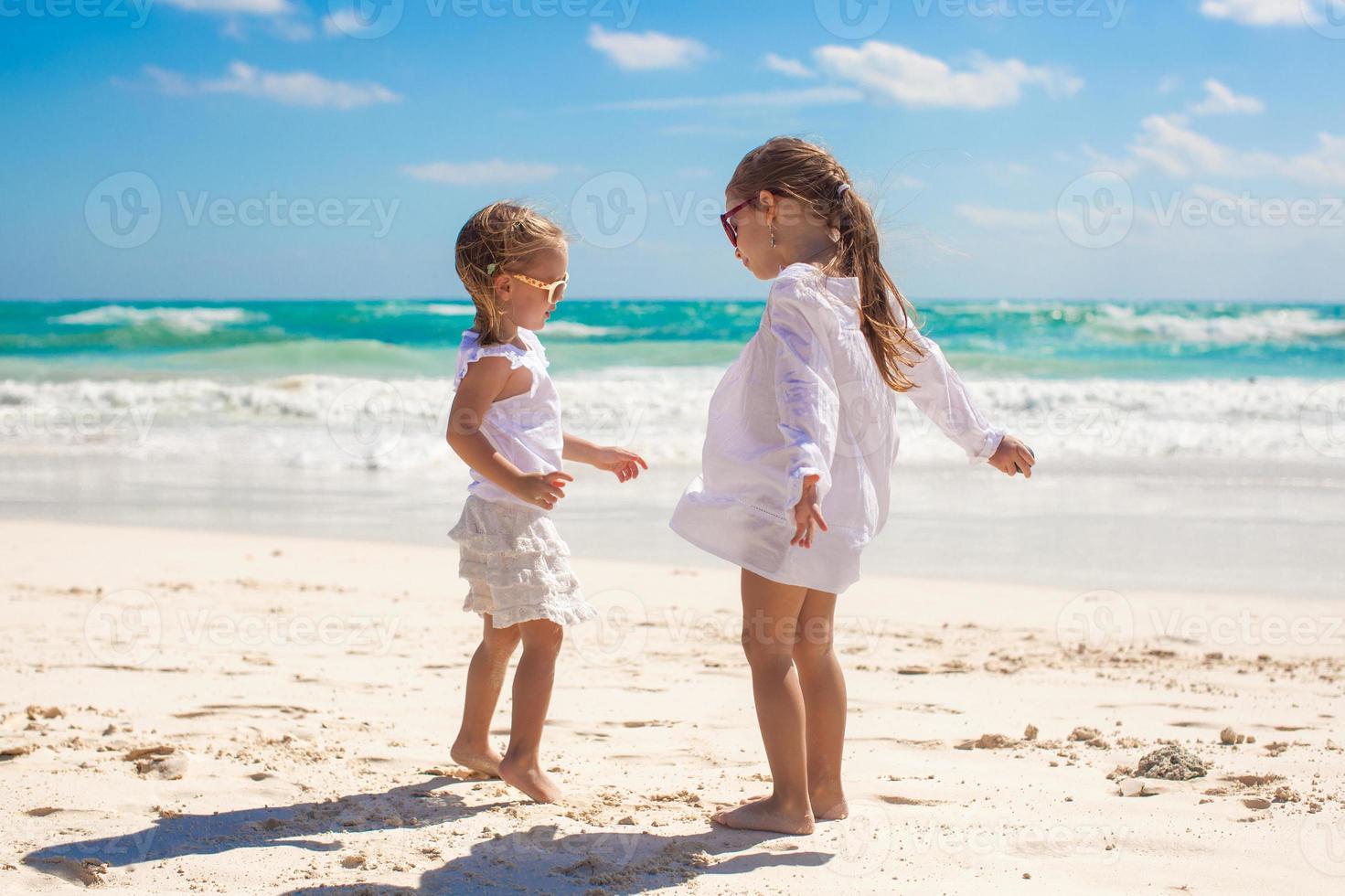 twee weinig zussen in wit kleren hebben pret Bij tropisch Mexico strand foto