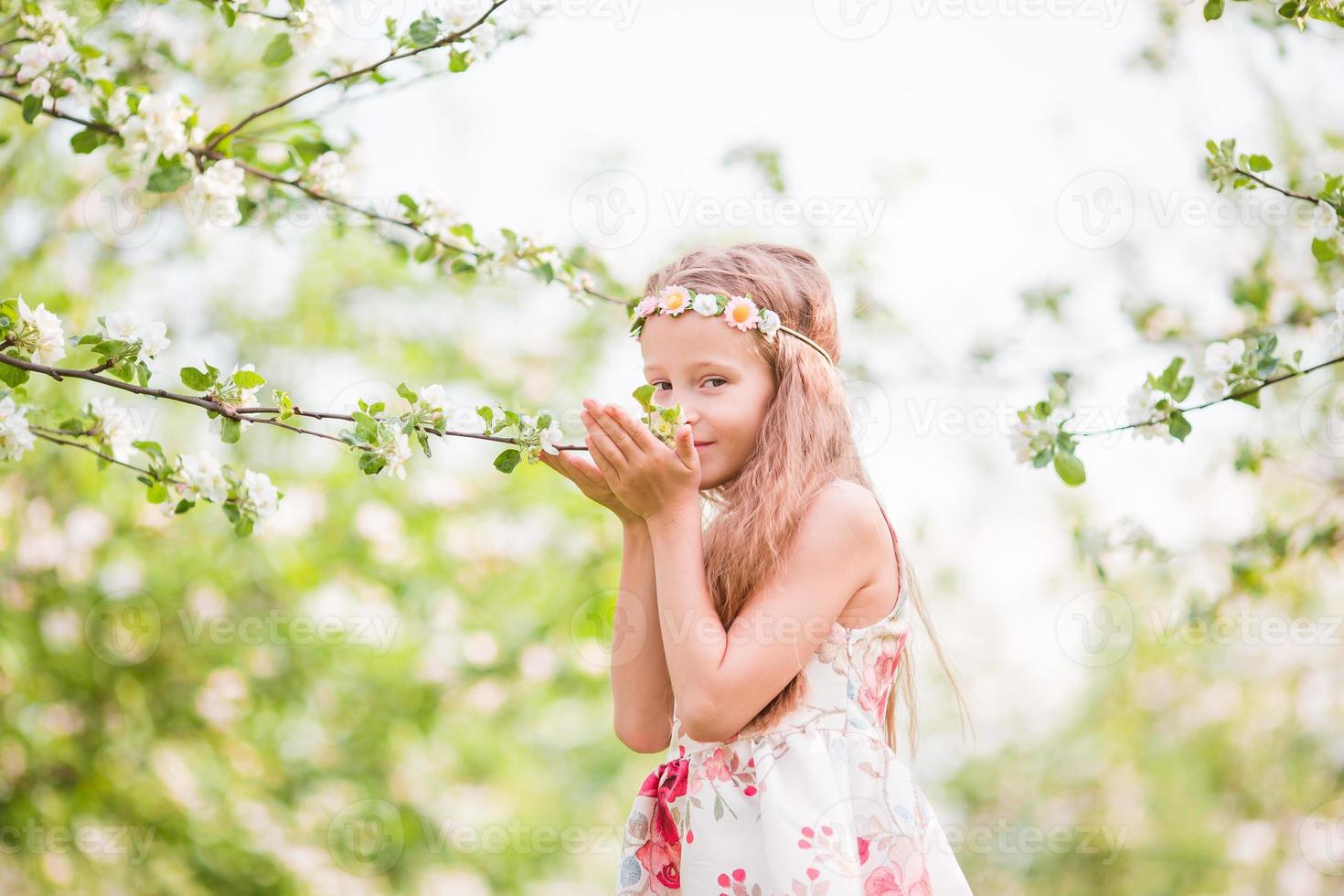 weinig mooi meisje genieten van geur in een bloeiend voorjaar appel tuin foto
