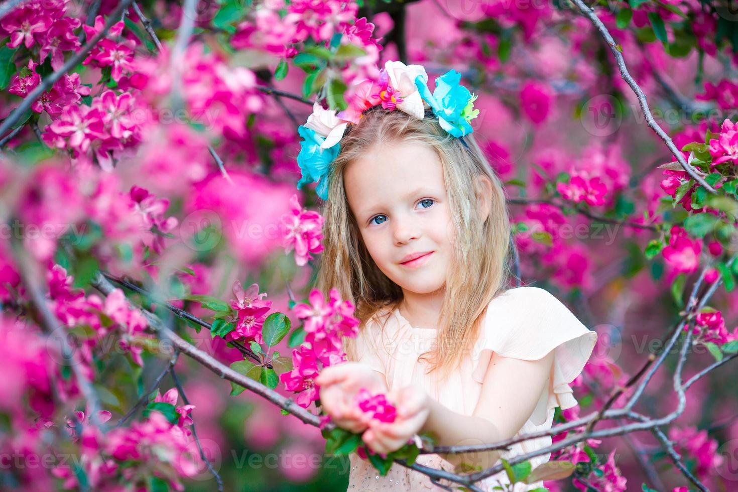 portret van aanbiddelijk weinig meisje in in bloeiend appel boom tuin Aan voorjaar dag foto