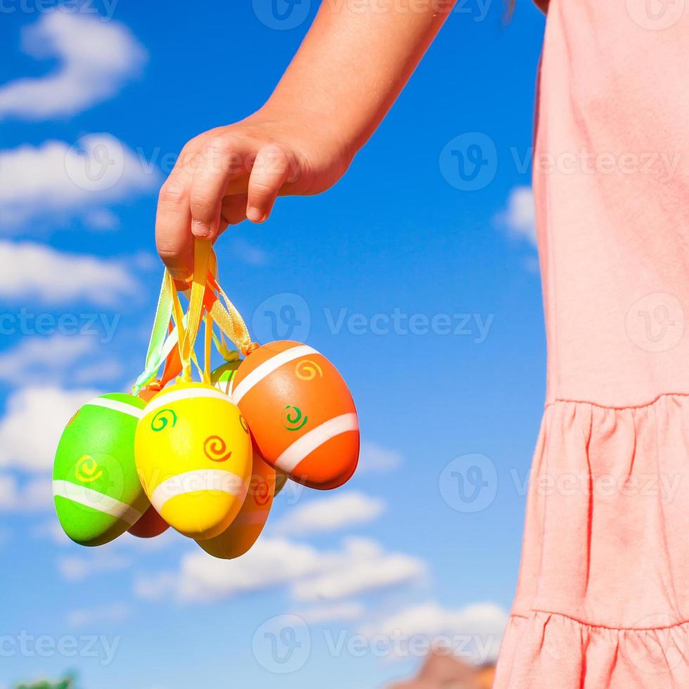 detailopname kleurrijk Pasen eieren in de handen van weinig mooi meisje foto