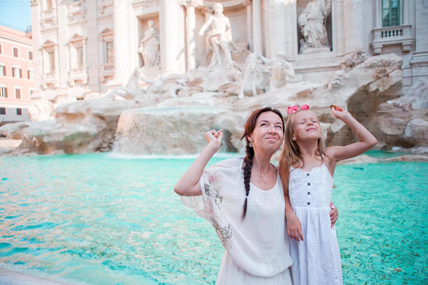 reizen familie mam en meisje troebelen munt Bij Trevi fontein, Rome, Italië voor mooi zo geluk. gelukkig familie genieten hun Italiaans vakantie vakantie in Europa. weinig meisje maken een wens naar komen rug. foto