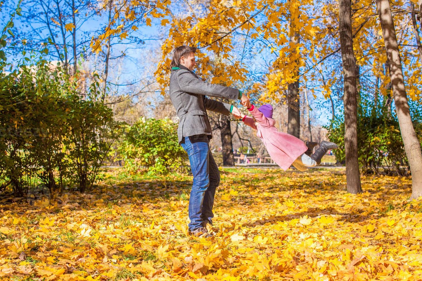 weinig meisje met gelukkig vader hebben pret in herfst park Aan een zonnig dag foto
