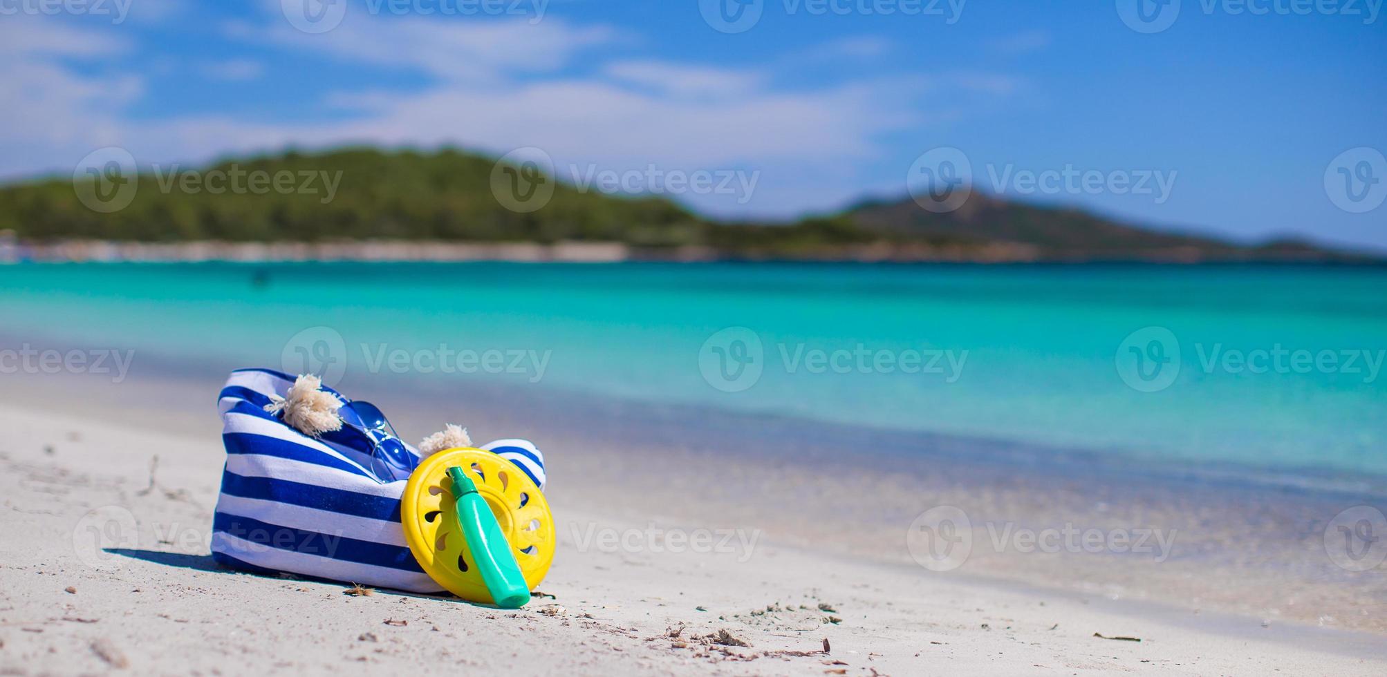 streep tas, rietje hoed, sunblock en frisbee Aan wit zanderig tropisch strand foto