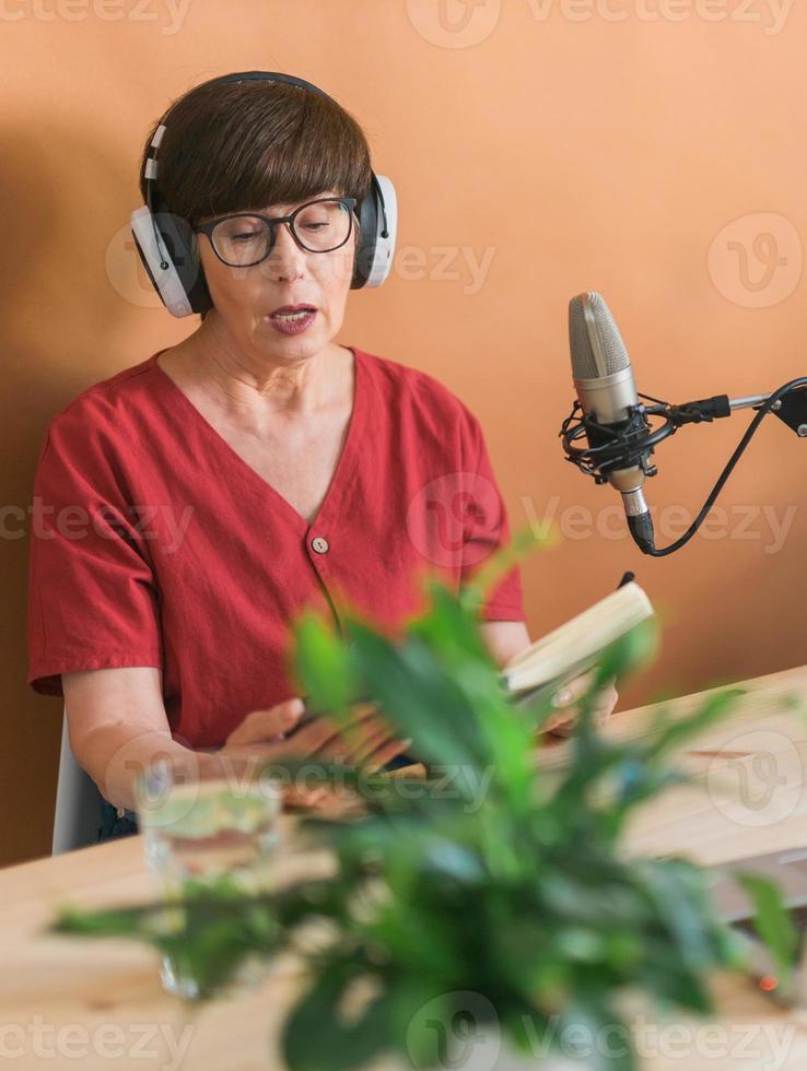 middelbare leeftijd vrouw radio presentator pratend in microfoon en lezing nieuws - radio uitzending online concept foto