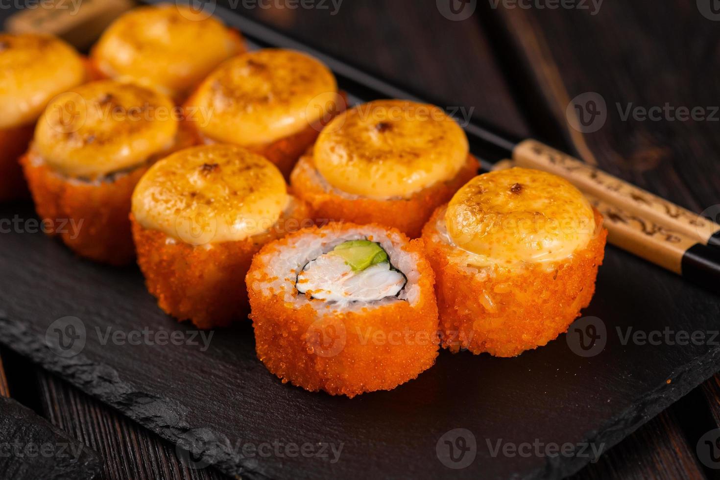 sushi rollen met krab, avocado en tobiko kaviaar geserveerd Aan zwart bord detailopname - Japans Aziatisch voedsel foto