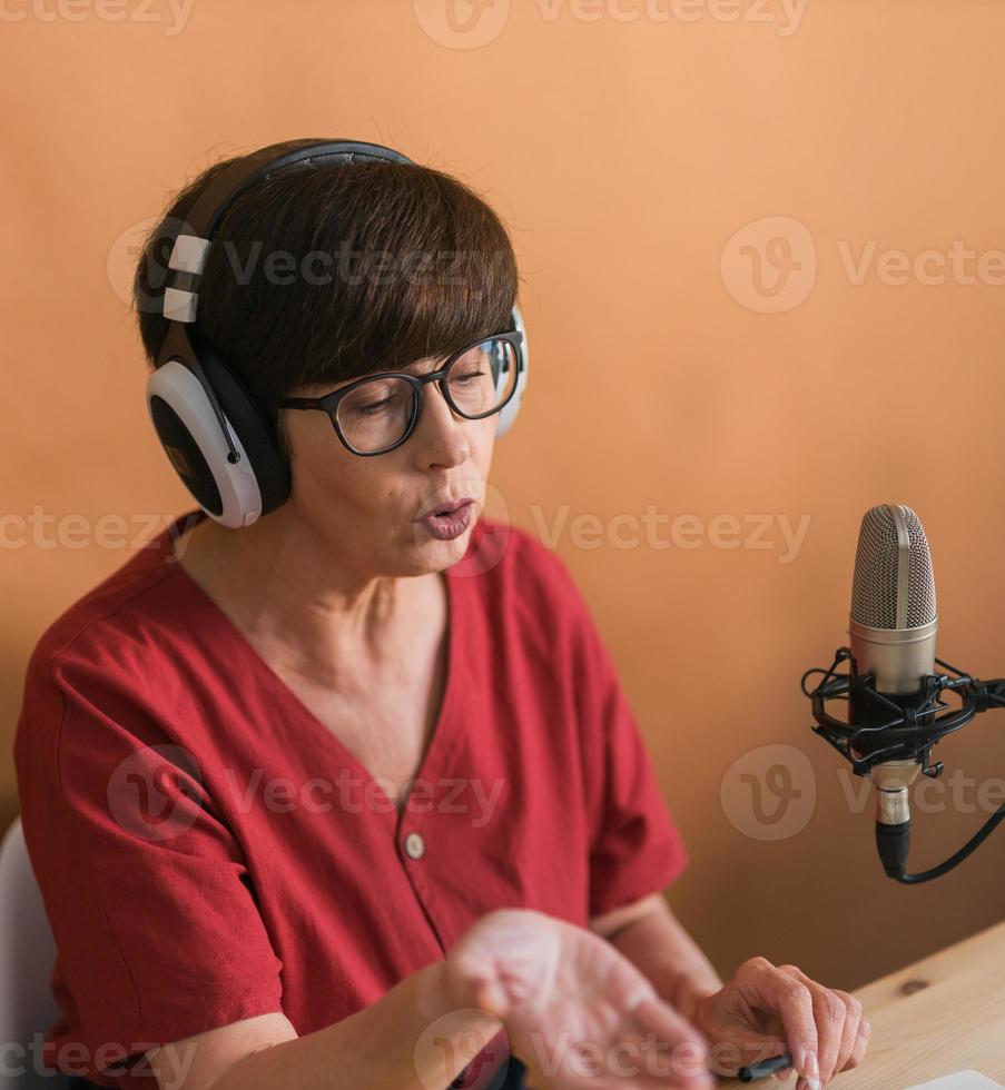 portret van volwassen vrouw vervelend hoofdtelefoons en pratend Bij online radio station - podcast en uitzending concept foto