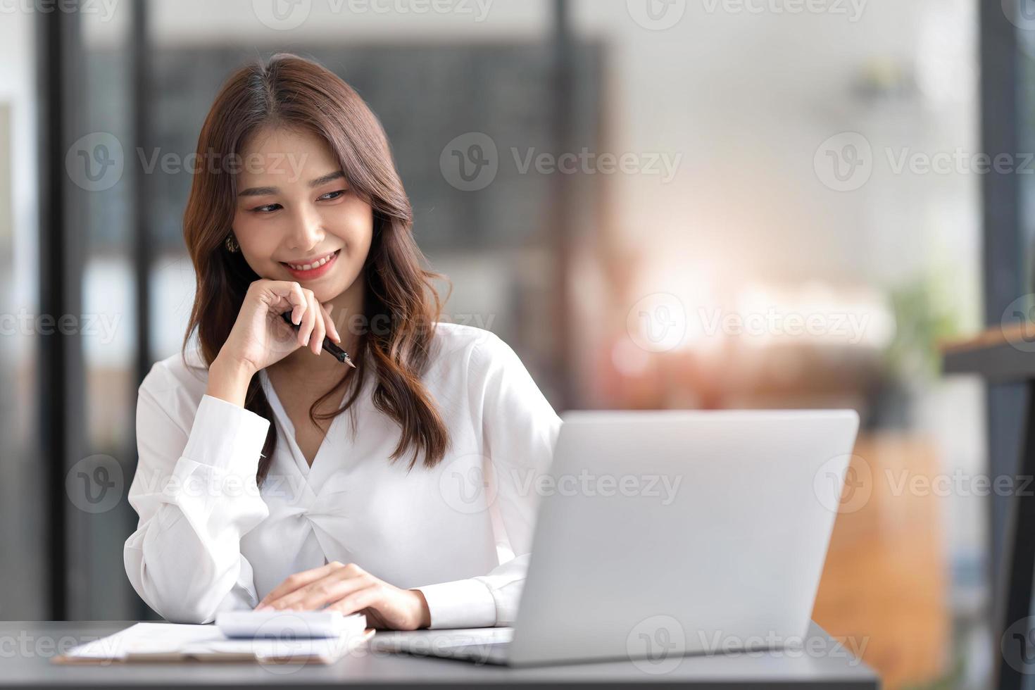 jong vrouw werken Aan een laptop in de kantoor. Aziatisch zakenvrouw zittend Bij haar werkplaats in de kantoor. mooi freelancer vrouw werken online Bij haar huis. foto