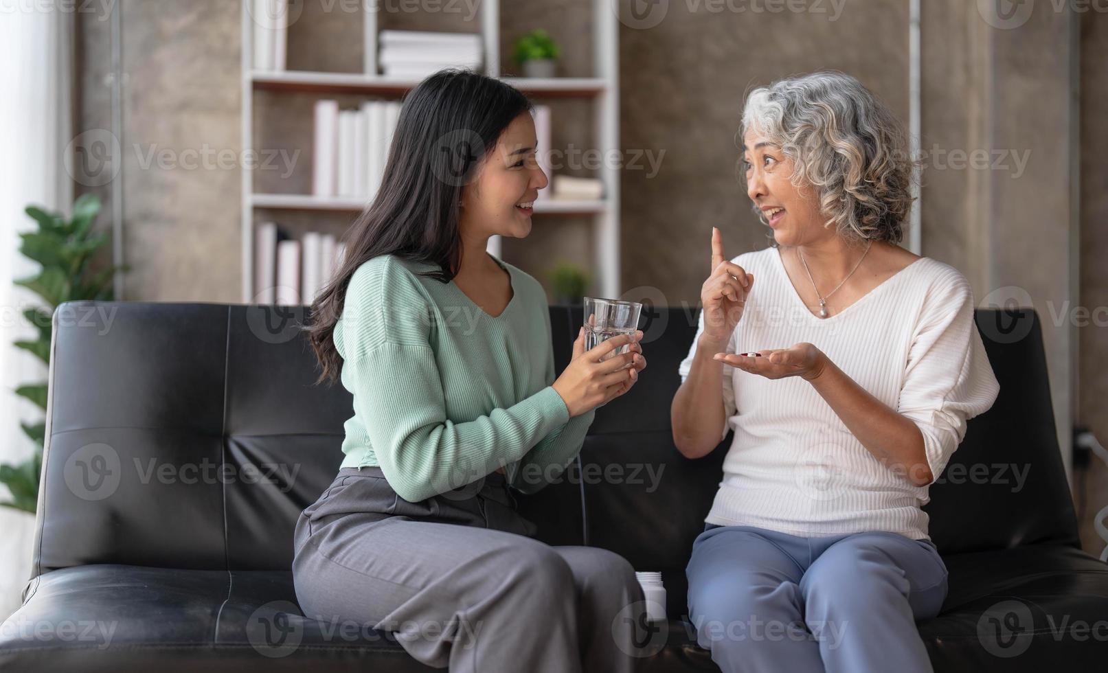 jong Aziatisch vrouw nemen zorg en geven een glas van water en genomen dagelijks geneeskunde of vitamine supplementen, ouderen gezondheidszorg en grootmoeder. foto