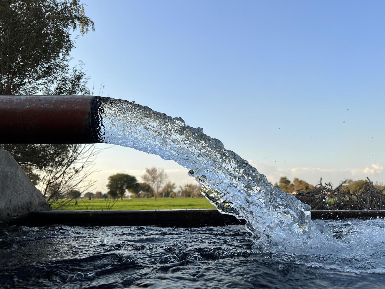 irrigatie water stromen van pijp naar kanaal voor landbouw velden foto