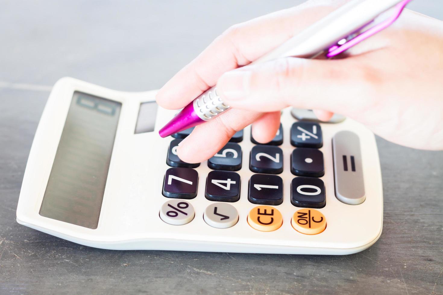 vrouw hand met een rekenmachine en een pen foto