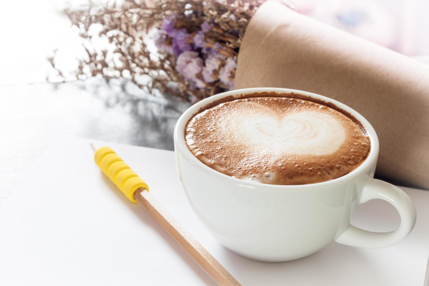 koffiekopje met blocnote en potlood op een grijze achtergrond foto