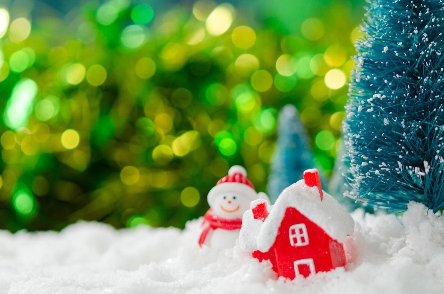 miniatuursneeuwman en huis in sneeuw foto