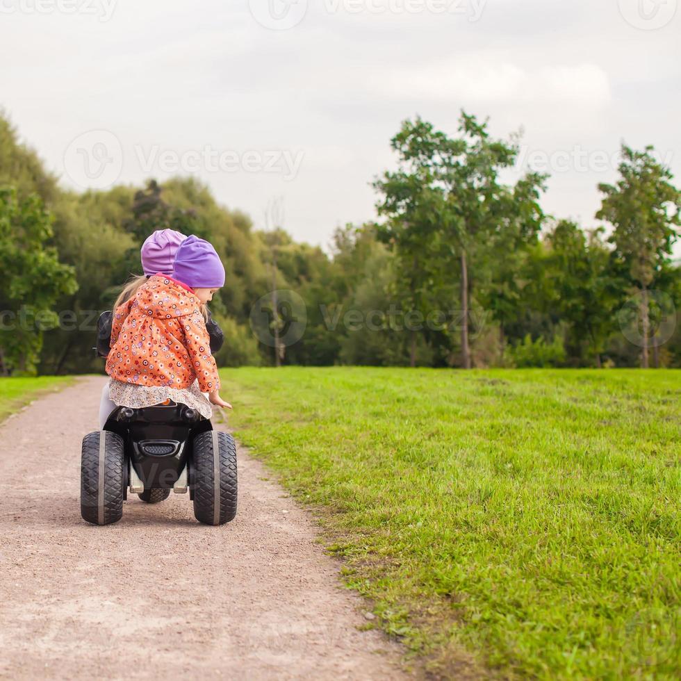 terug visie van aanbiddelijk weinig meisjes rijden een motor buiten foto