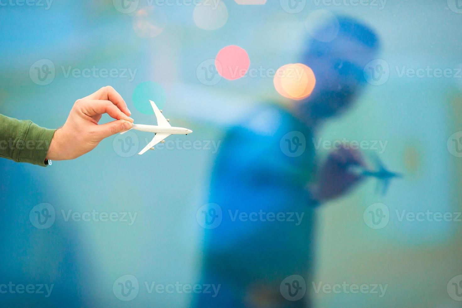 detailopname hand- Holding een vliegtuig model- speelgoed- Bij de luchthaven achtergrond groot venster foto