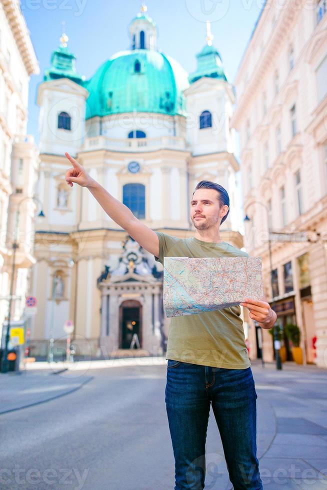 Mens toerist met een stad kaart in Europa straat. Kaukasisch jongen op zoek met kaart van Europese stad. foto