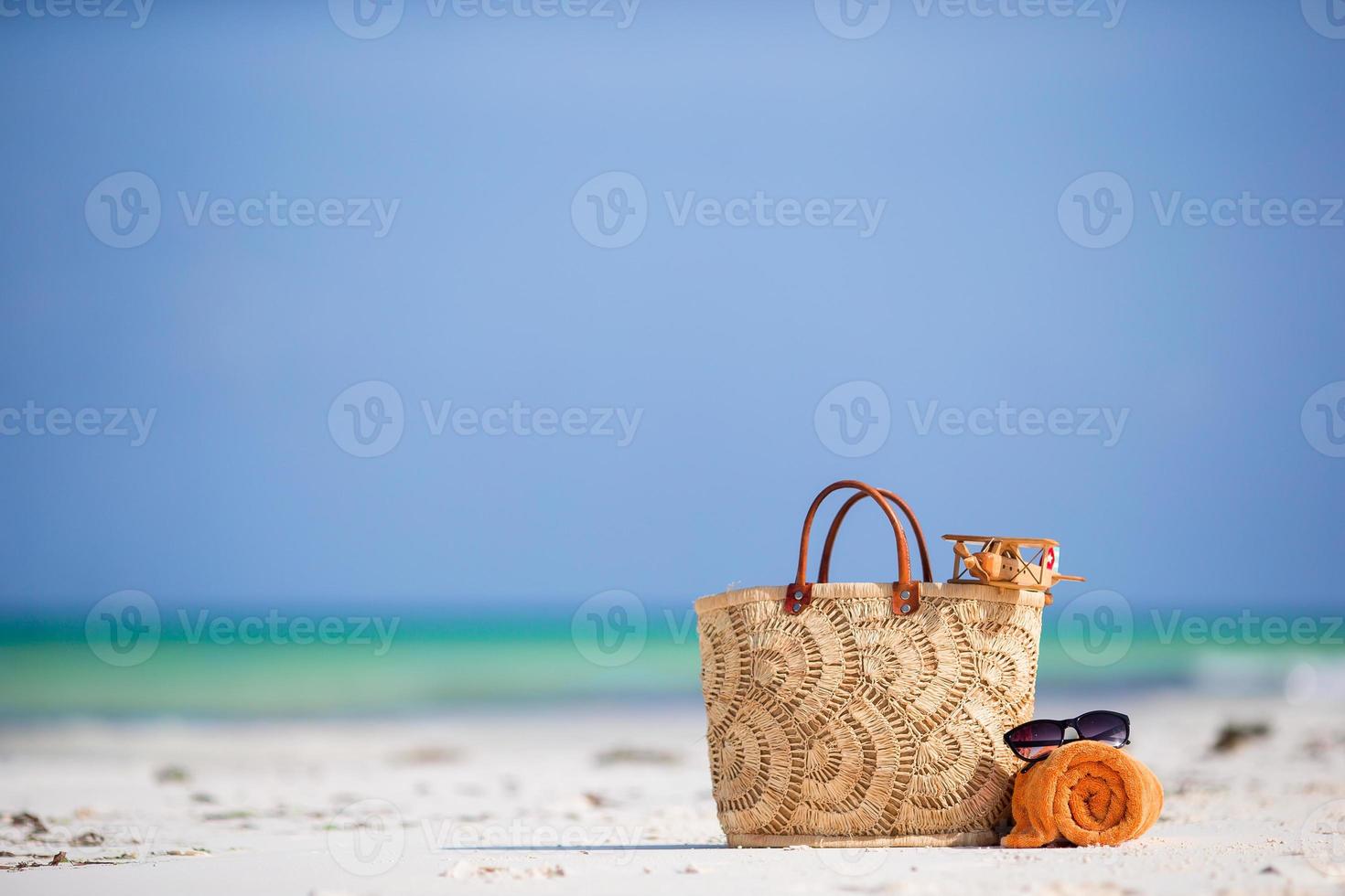 strandaccessoires - speelgoedvliegtuig, strozak, oranje handdoek en zonnebril op het strand foto