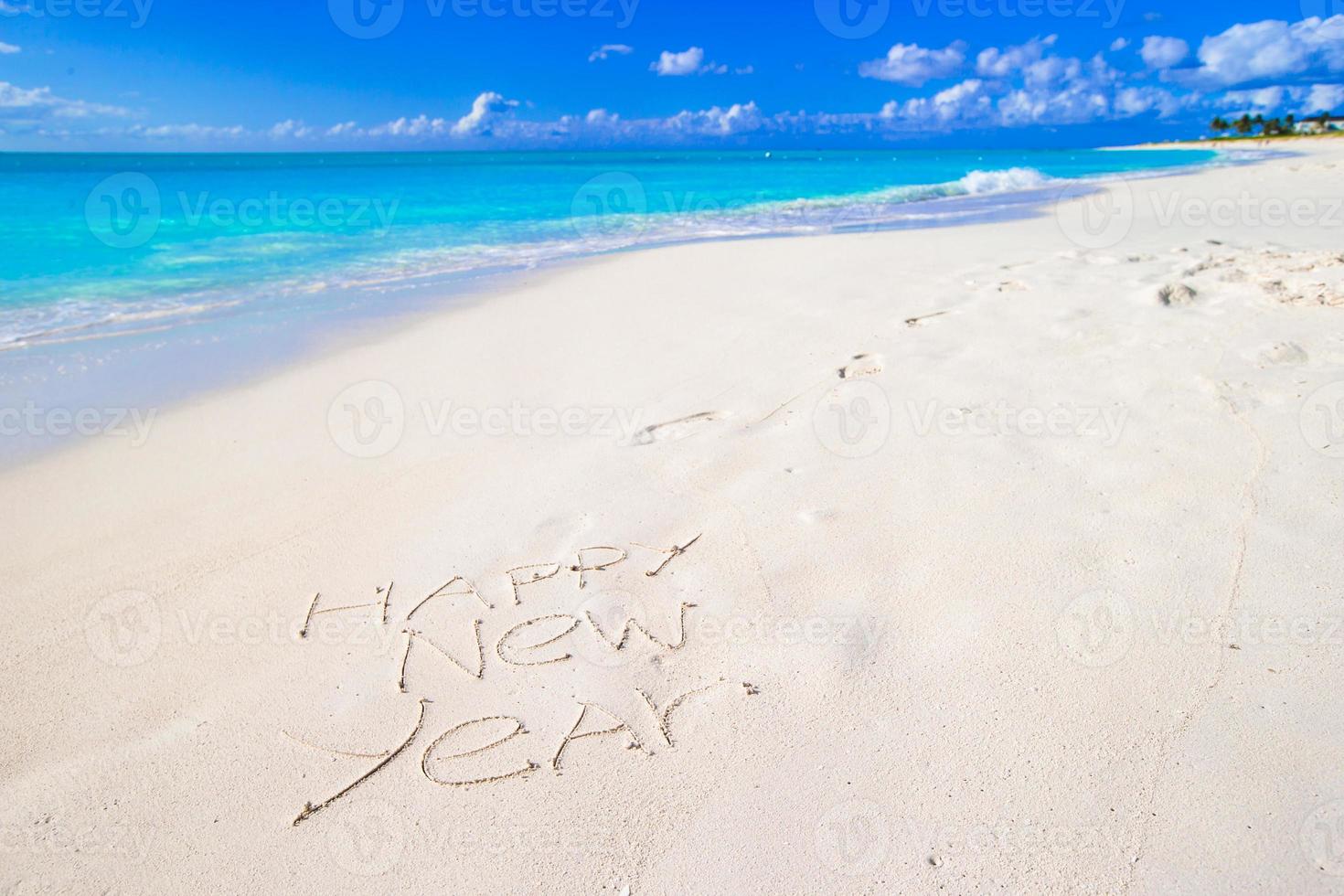 gelukkig nieuw jaar geschreven Aan strand wit zand met rood de kerstman hoed foto