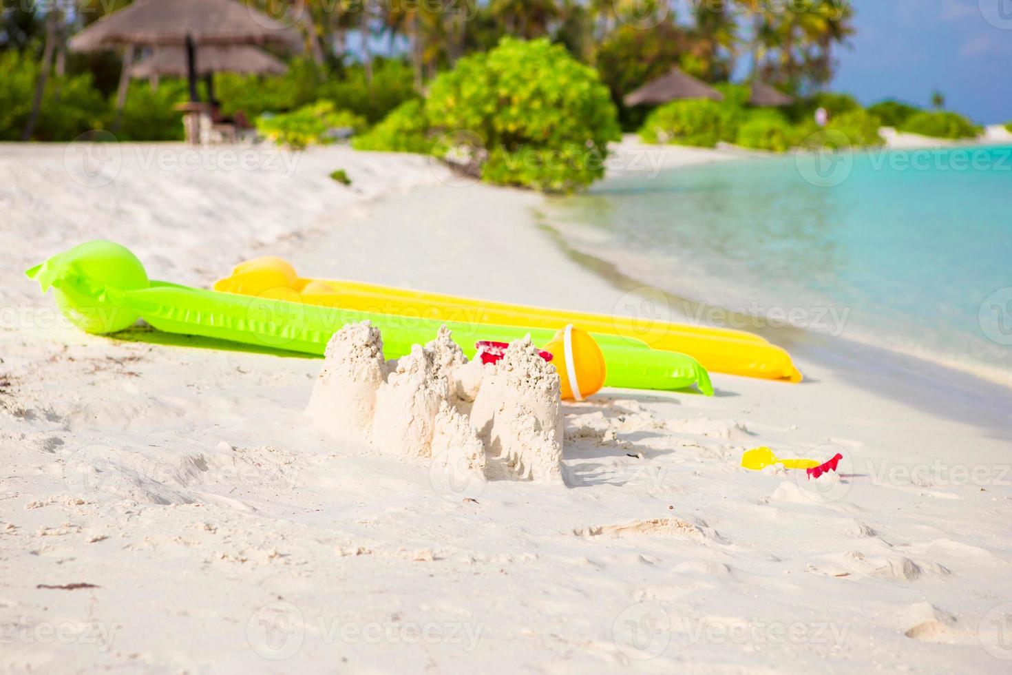 Zandkasteel Bij wit strand met plastic kinderen speelgoed Aan perfect eiland foto