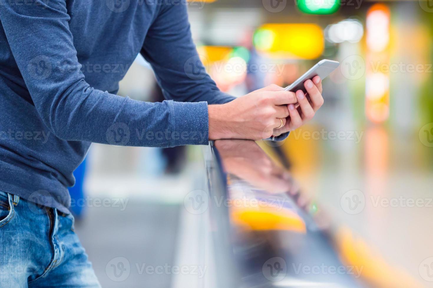 Mens met rugzak Holding cel telefoon Bij luchthaven aan het wachten de vlucht foto