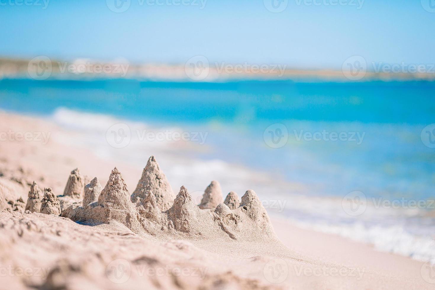 Zandkasteel Bij wit tropisch strand met plastic kinderen speelgoed foto