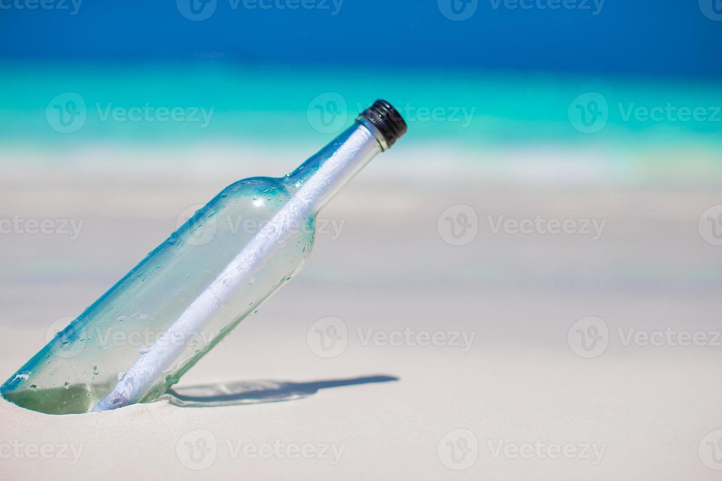 fles met een bericht begraven in de wit zand foto