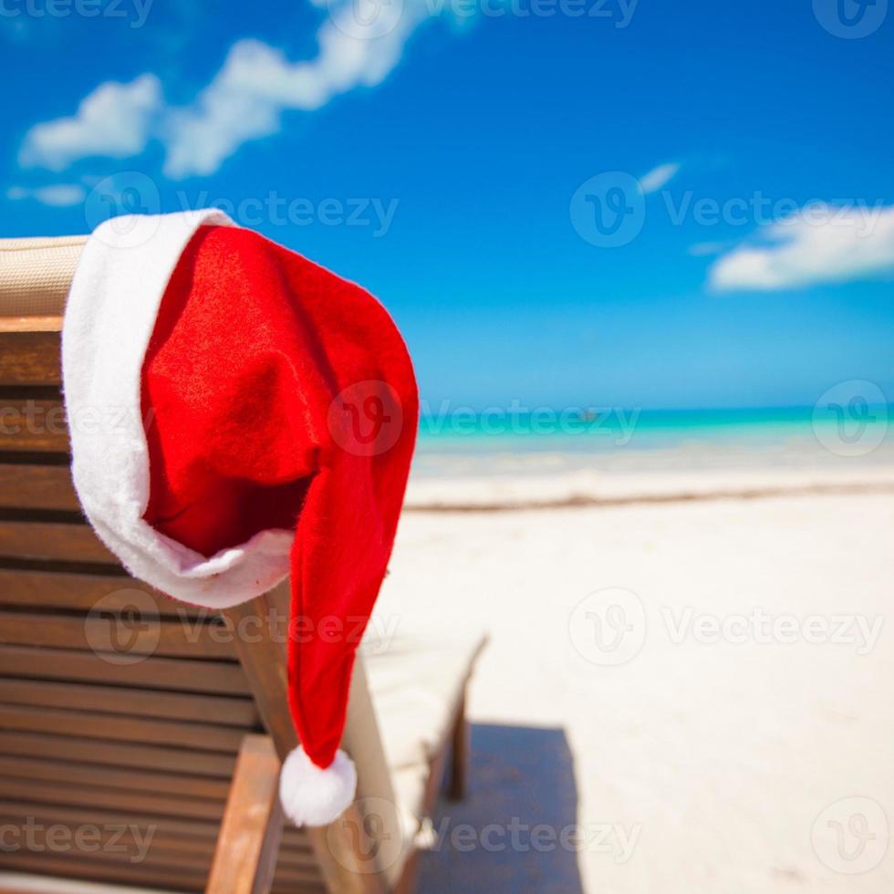 rood de kerstman hoed Aan stoel longue Bij tropisch caraïben strand foto