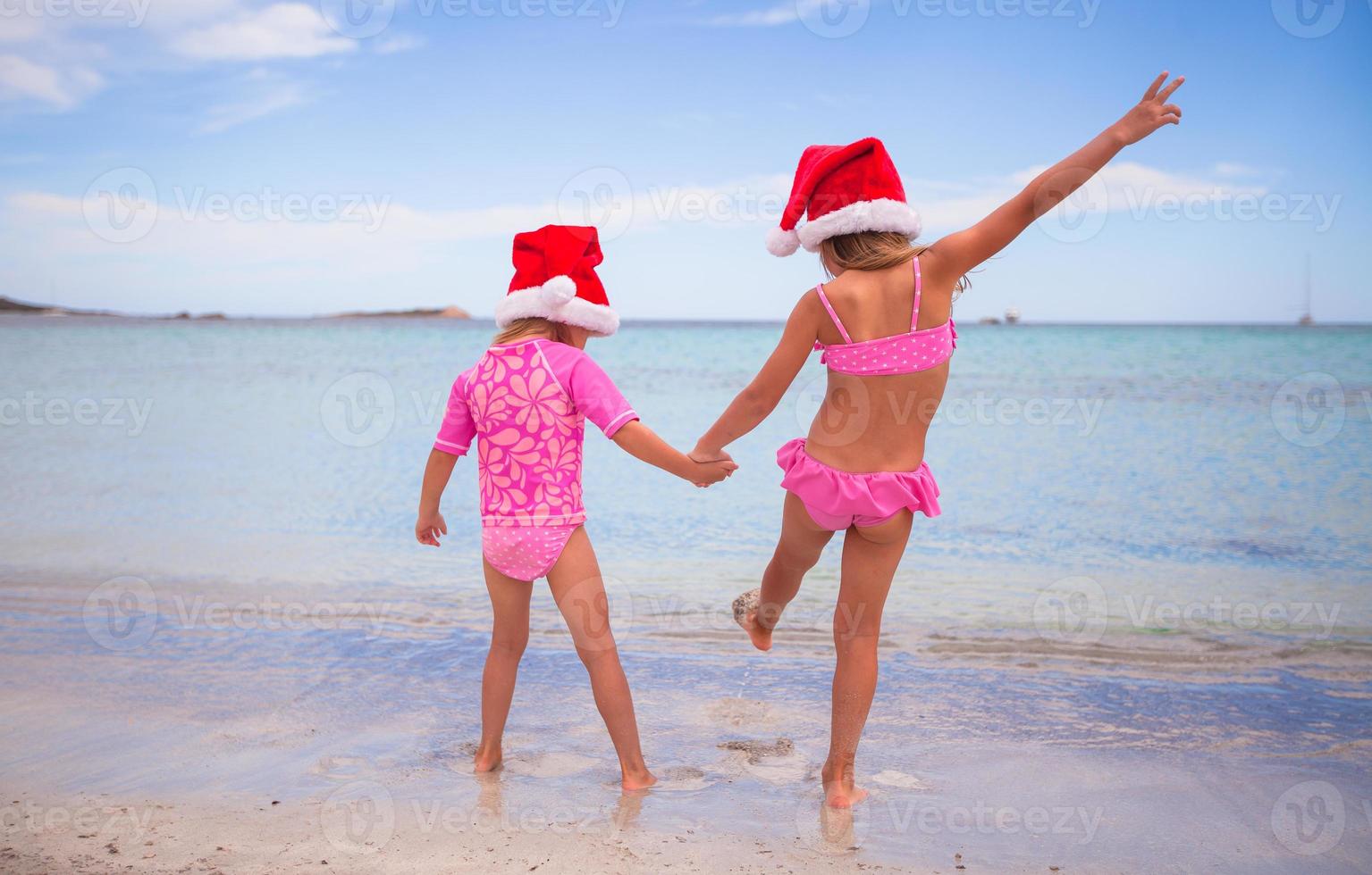 weinig aanbiddelijk meisjes in de kerstman hoeden gedurende strand vakantie foto