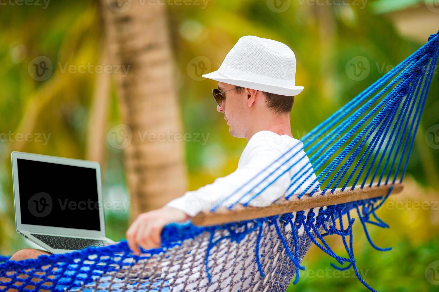 jong Mens met laptop Bij hangmat Aan tropisch vakantie foto