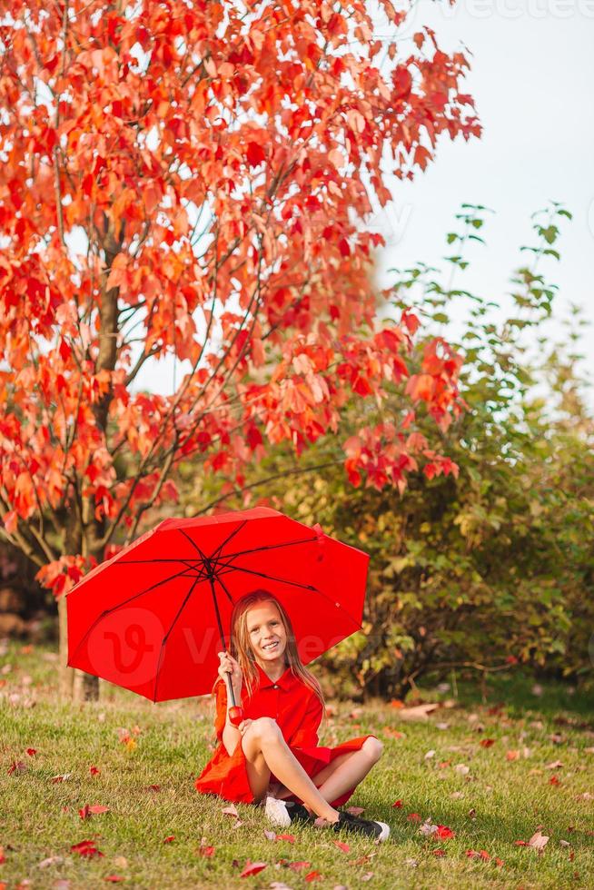 gelukkig kind meisje lacht onder rood paraplu foto